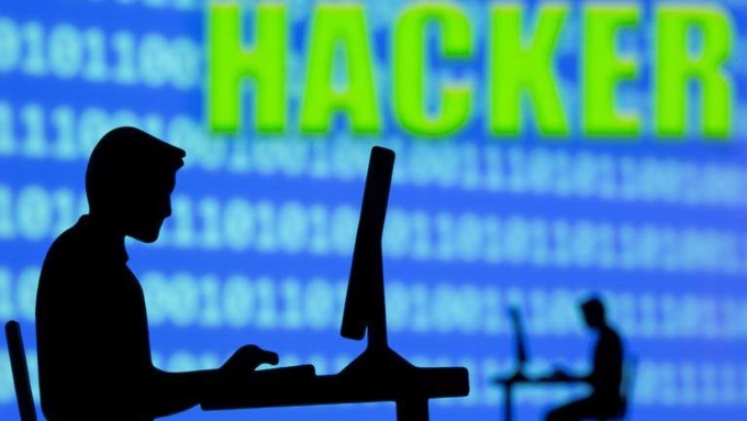 Một mô hình người sử dụng máy tính, phía sau là màn hình với dòng chữ hacker. Ảnh: Reuters